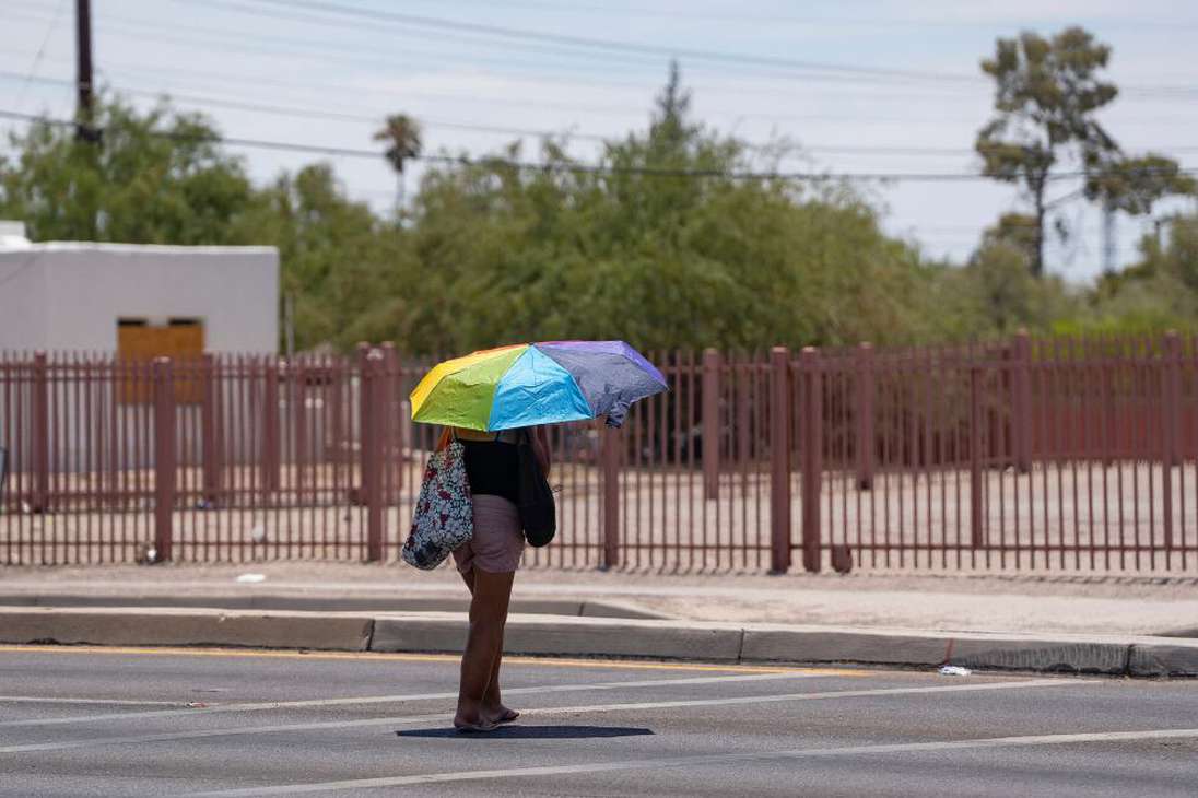 Una persona se protege del sol con un paraguas arco iris durante una ola de calor en Tucson, Arizona, el 15 de julio de 2023.