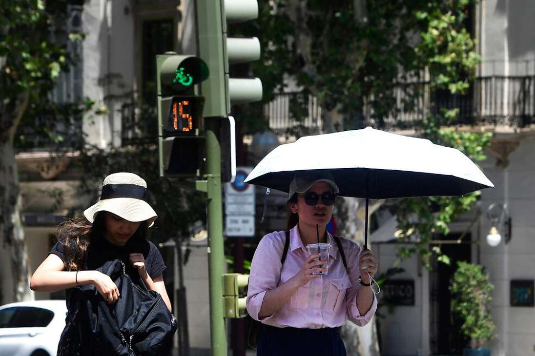 Turistas se esconden del sol mientras pasean por una calle de Sevilla, el 16 de julio de 2023.
