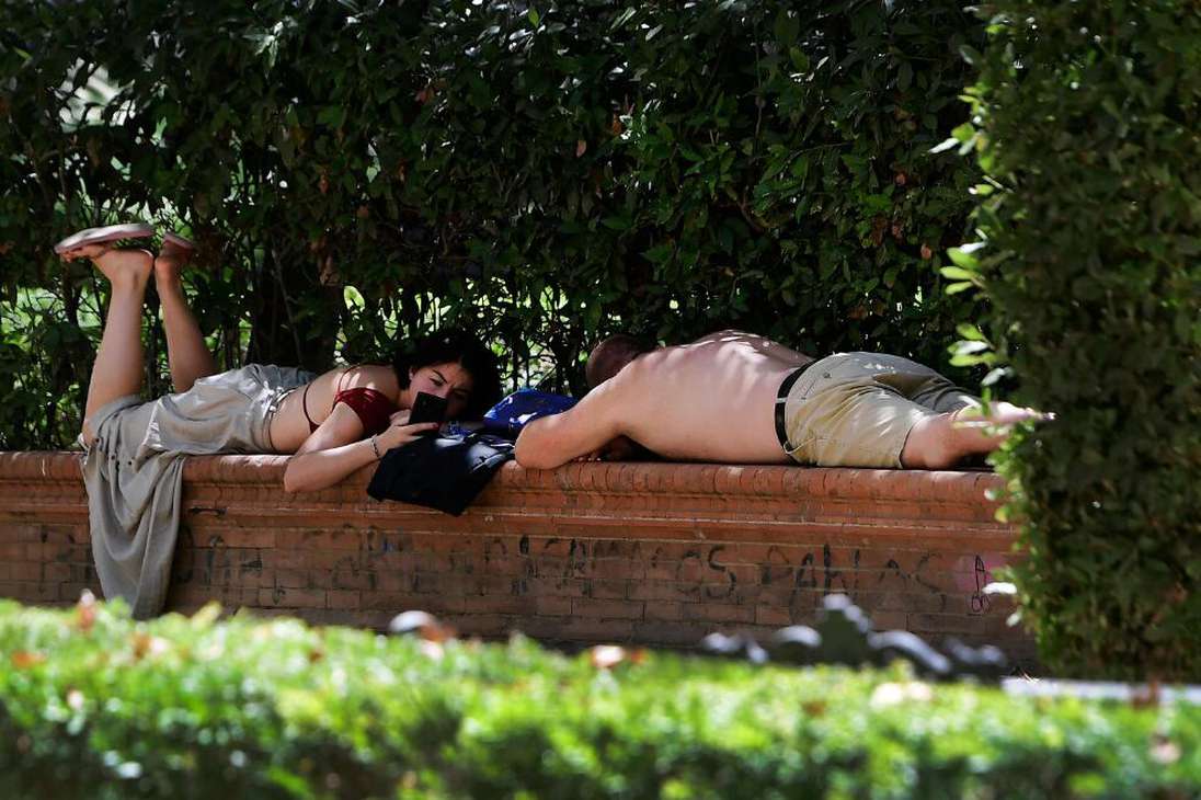 Una pareja se tumba en un banco para esconderse del sol en Sevilla, el 16 de julio de 2023.
