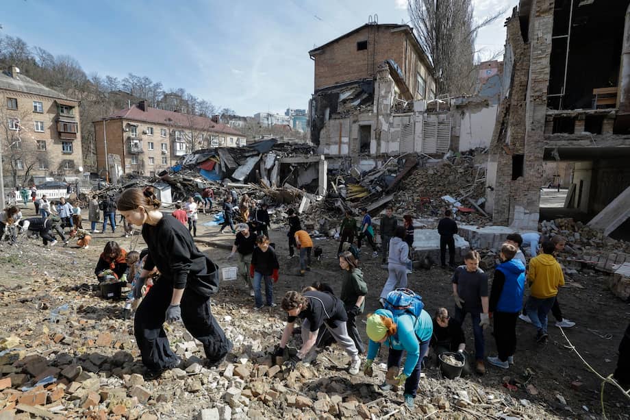 Estudiantes y voluntarios limpian los escombros de la academia de Kiev dañada por los bombardeos rusos.