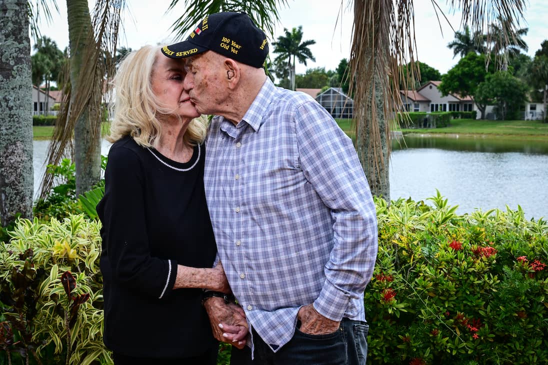 World War II veteran Harold Terens, 100, and his fiancee Jeanne Swerlin, 96, kiss during an interview, April 3, 2024, in Boca Raton, Florida.