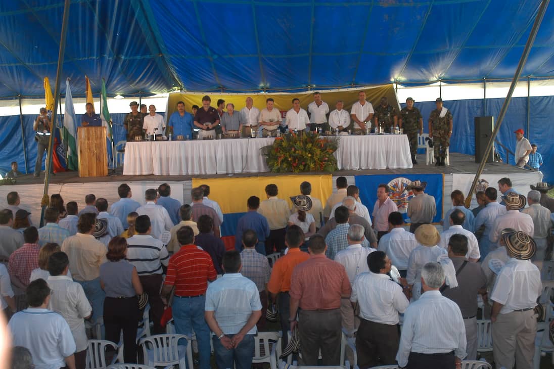 El 15 de julio de 2003, en la cancha del corregimiento de Santafé de Ralito, llegaron los delegados del gobierno, las AUC, la Iglesia Católica, medios de comunicación nacionales e internacionales y políticos nacionales a acompañar el acto.