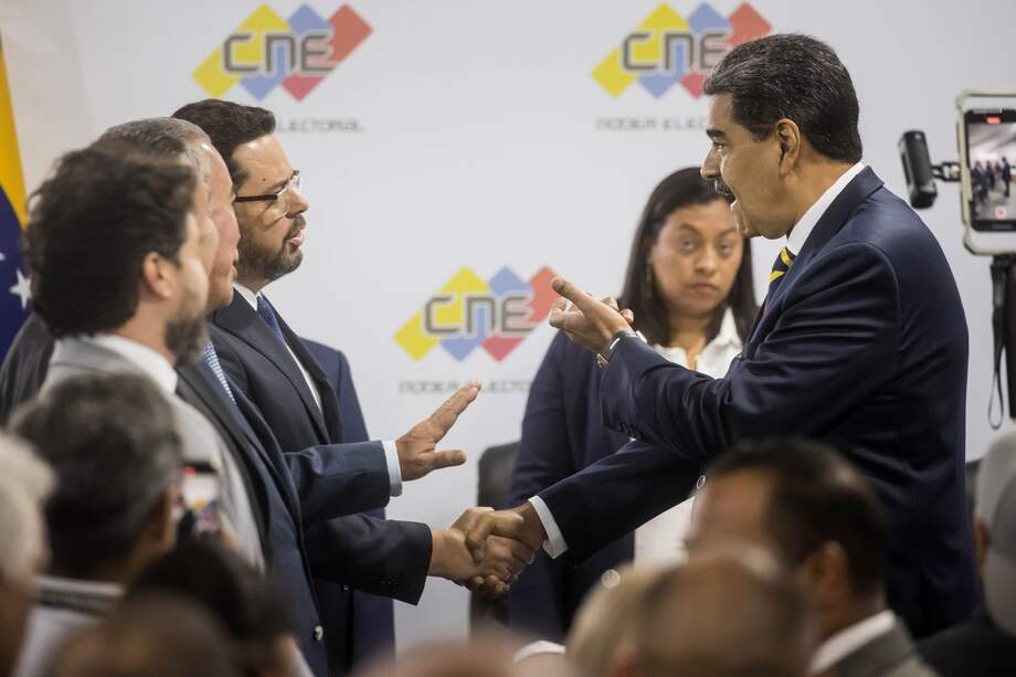 El presidente de Venezuela y aspirante a la reelección, Nicolás Maduro (d), saluda al también aspirante Antonio Ecarri en una reunión con candidatos en la sede del Consejo Nacional Electoral (CNE).