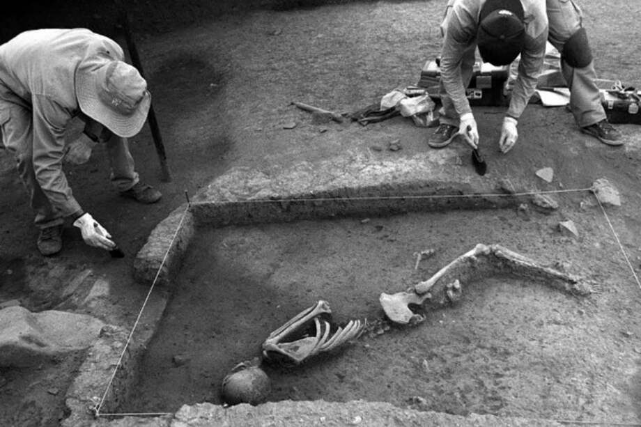 Foto en blanco y negro publicada por el Ministerio de Cultura peruano el 24 de octubre de 2018 de arqueólogos que trabajan en un esqueleto de 3.000 años descubierto en el sitio arqueológico de Marcavalle, en el valle de Cuzco, Perú. / AFP