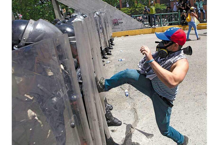Un venezolano se ubica en medio de una confrontación entre estudiantes y la policía en Caracas, donde las guarimbas persisten. / AFP
