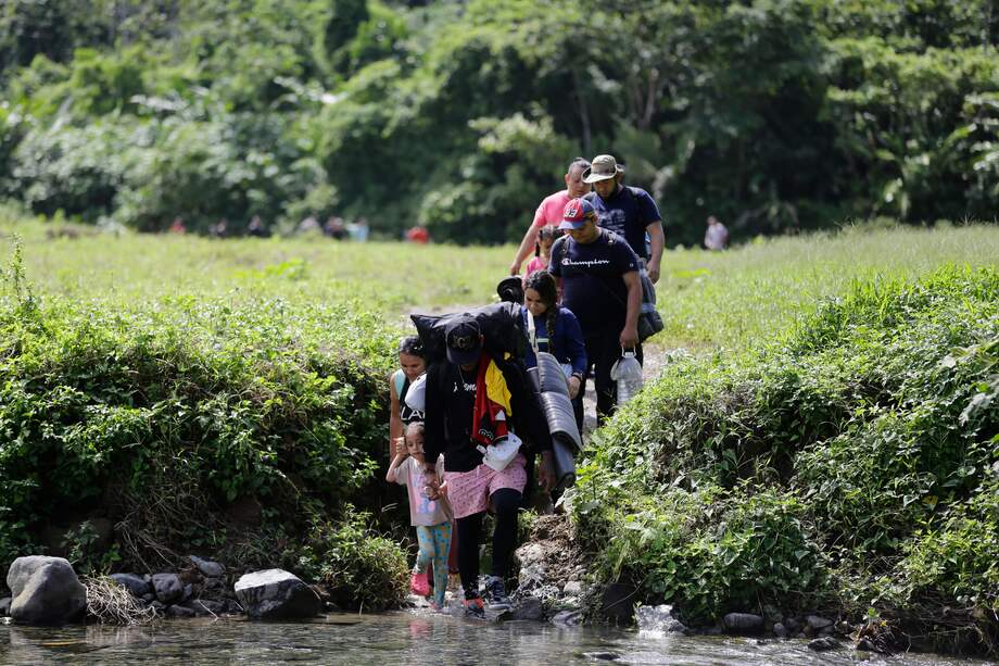Unos migrantes acompañados con niños pequeños caminan en el sector de Cañas Blancas en Darién (Panamá).