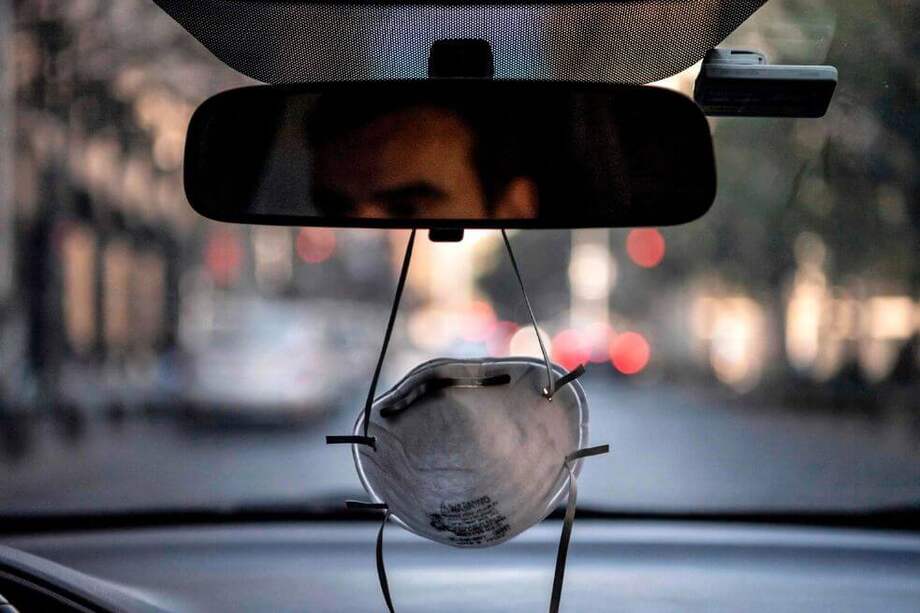 Una máscara facial cuelga de un espejo retrovisor en un automóvil en Santiago en medio de la nueva pandemia de coronavirus. / AFP