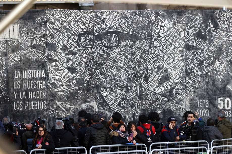 Personas se manifiestan durante un acto ciudadano en Conmemoración de los 50 años del Golpe de Estado teniendo de fondo una imagen del Salvador Allende, hoy a las afueras del Palacio de La Moneda en Santiago (Chile). 